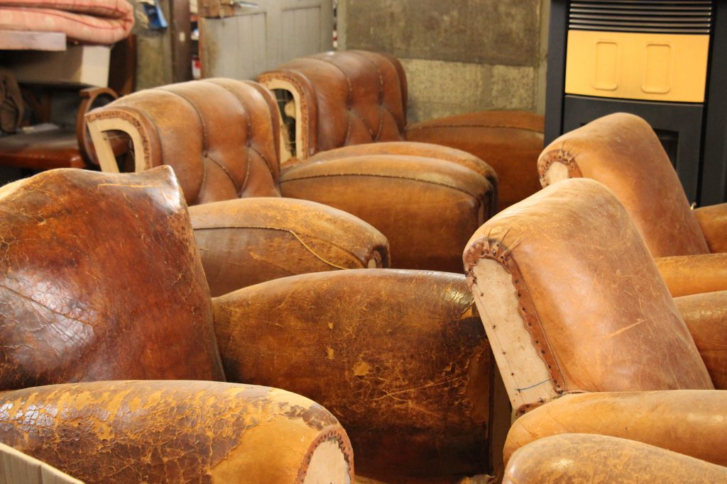 Quelques fauteuils club vintage en cuir ancien qui attendent leur rénovation dans notre atelier du cuir - Bretagne à Callac.