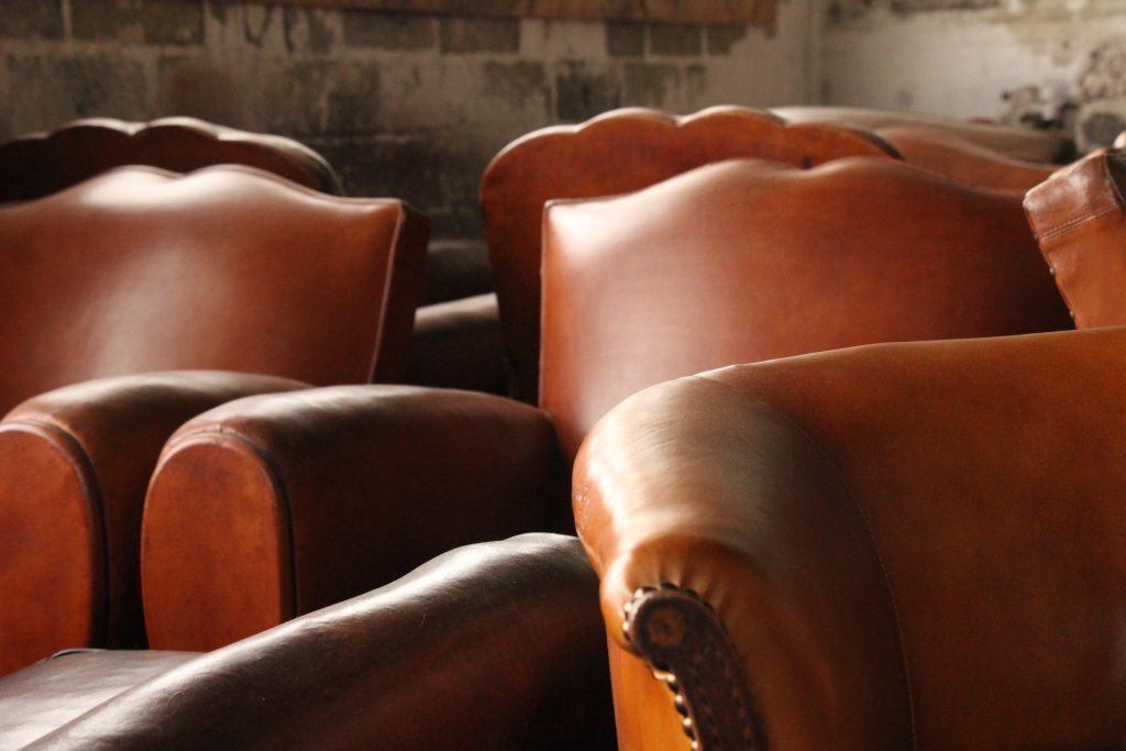 Quelques fauteuils club moustache en cuir ancien et fauteuils club à dossier fleur rénovés et patinés avec soin à notre atelier du cuir - Bretagne à Callac